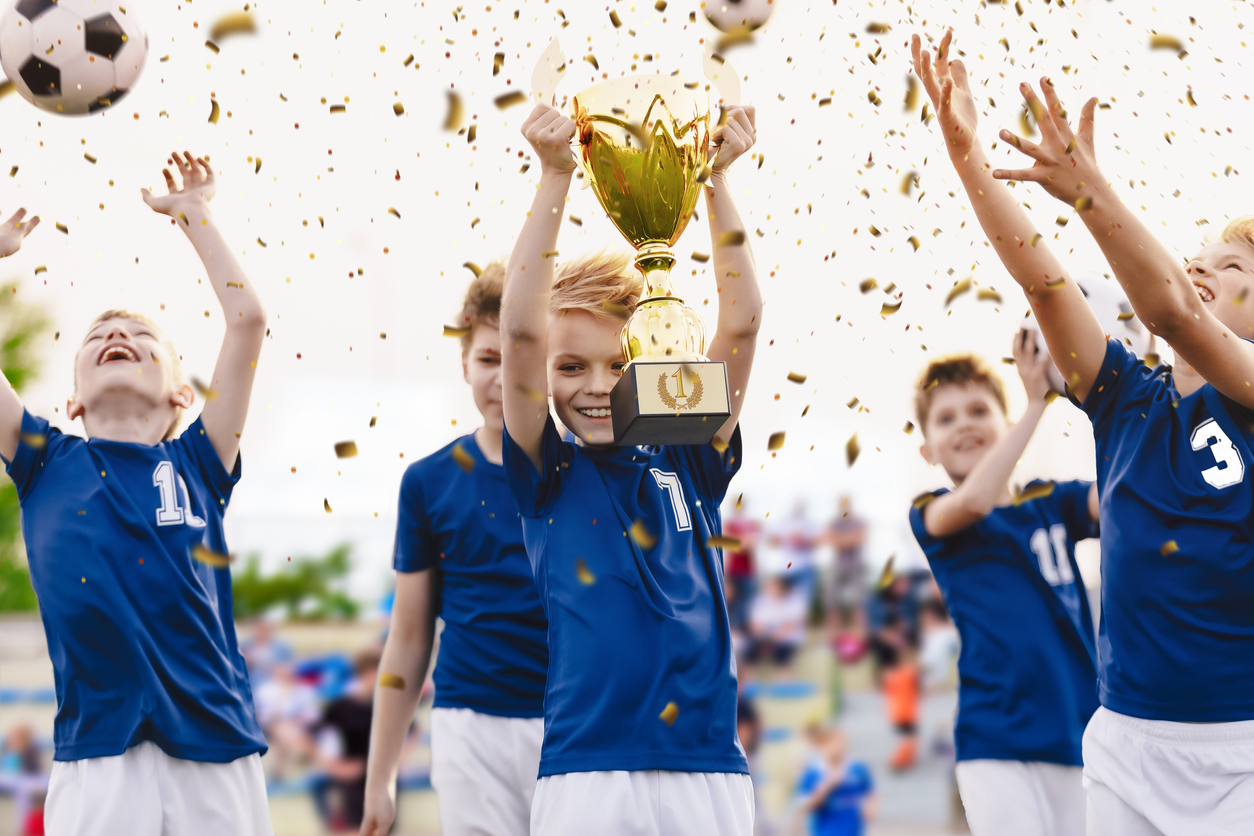 Champion youth soccer team with winning trophy. Boys football team celebrating victory in school competition by rising up golden cup. Happy kids as soccer tournament winners